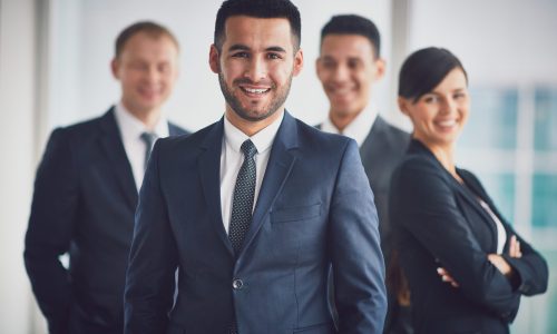 Portrait of confident business partners looking at camera with smiling leader in front